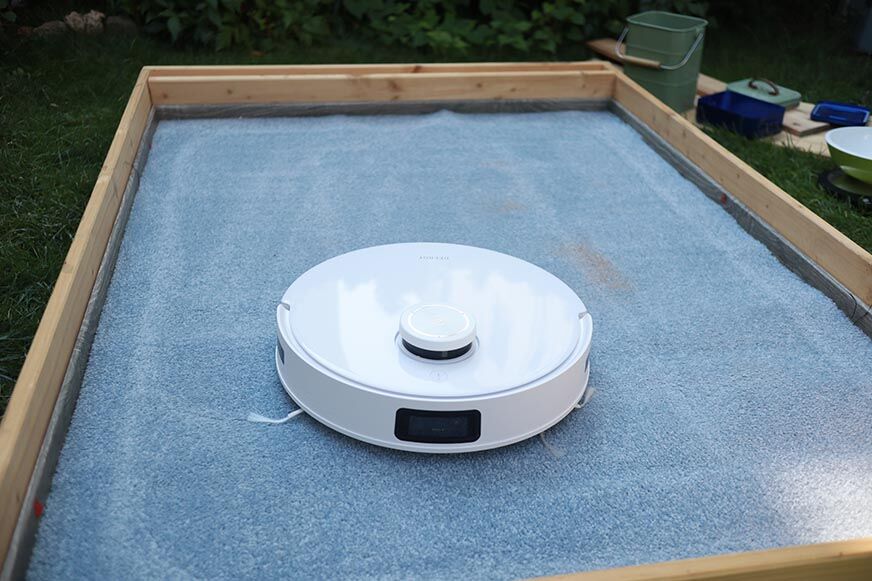 Ecovacs Deebot T10 reinigt im Test Sand auf einem hohen Teppich.